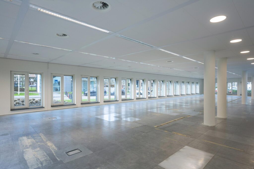 Leeg kantoorpand aan de De Cuserstraat met grote ramen en systeemplafond.